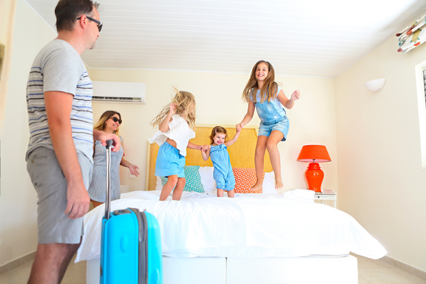 Family with three kids with luggage in hotel room