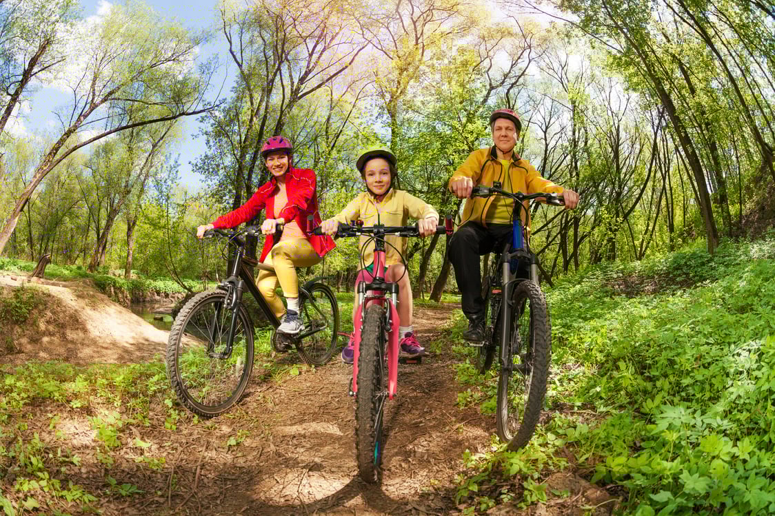 Happy Family Mountain Biking on Forest Trail